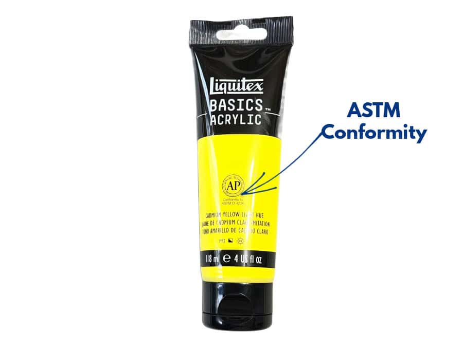 A tube of Liquitex Cadmium Yellow paint with an arrow indicating the ASTM conformity of the paint.