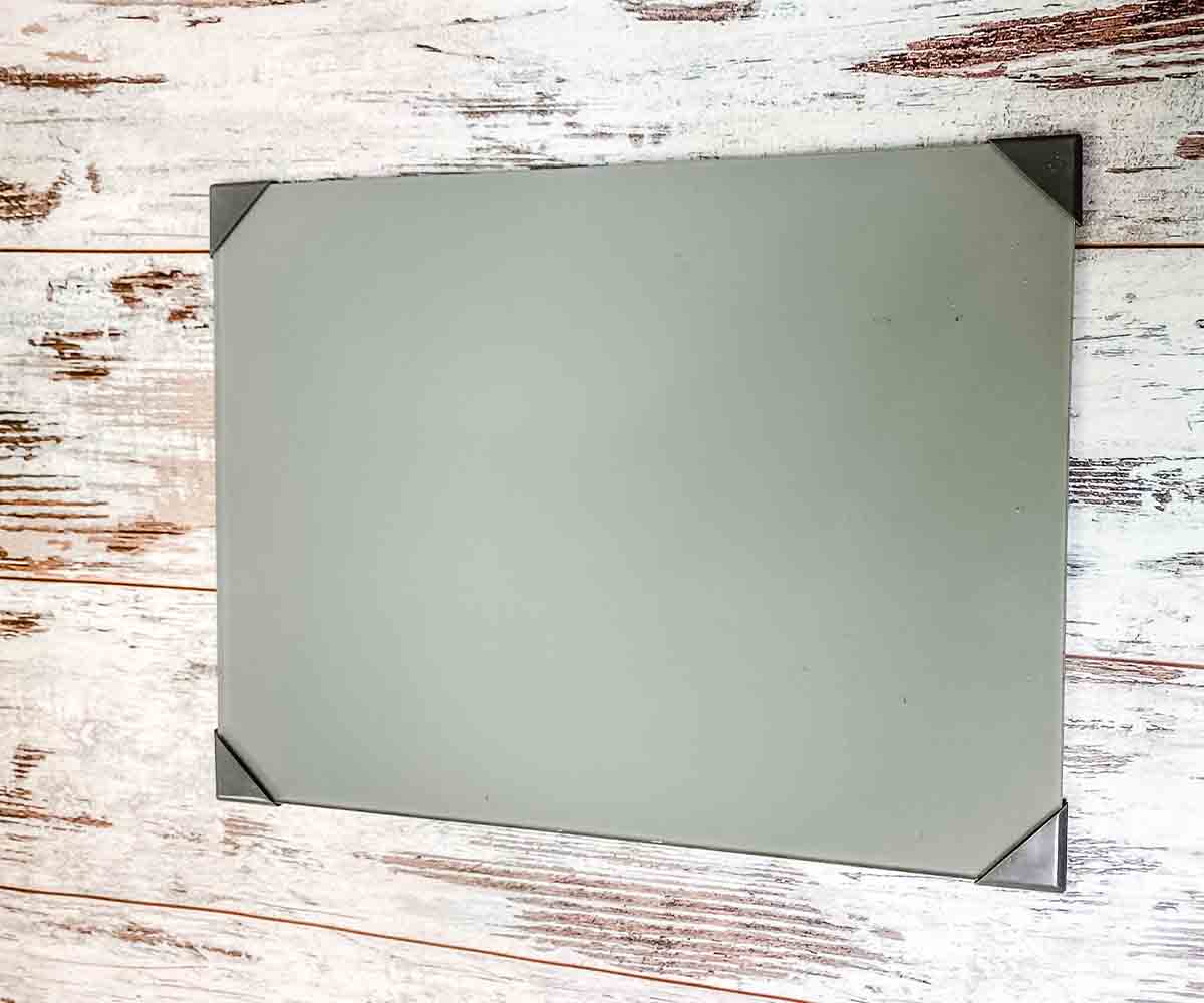 A grey glass artist's palette sitting on a wooden table.