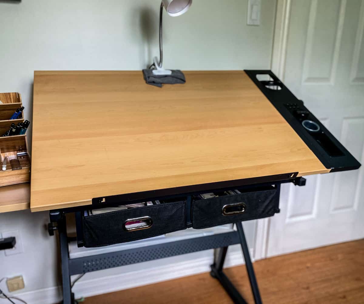 A tilted drawing desk with a lamp attached.