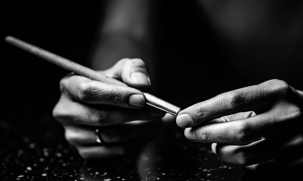 A black and white photo of an artists hands holding an artists brush.