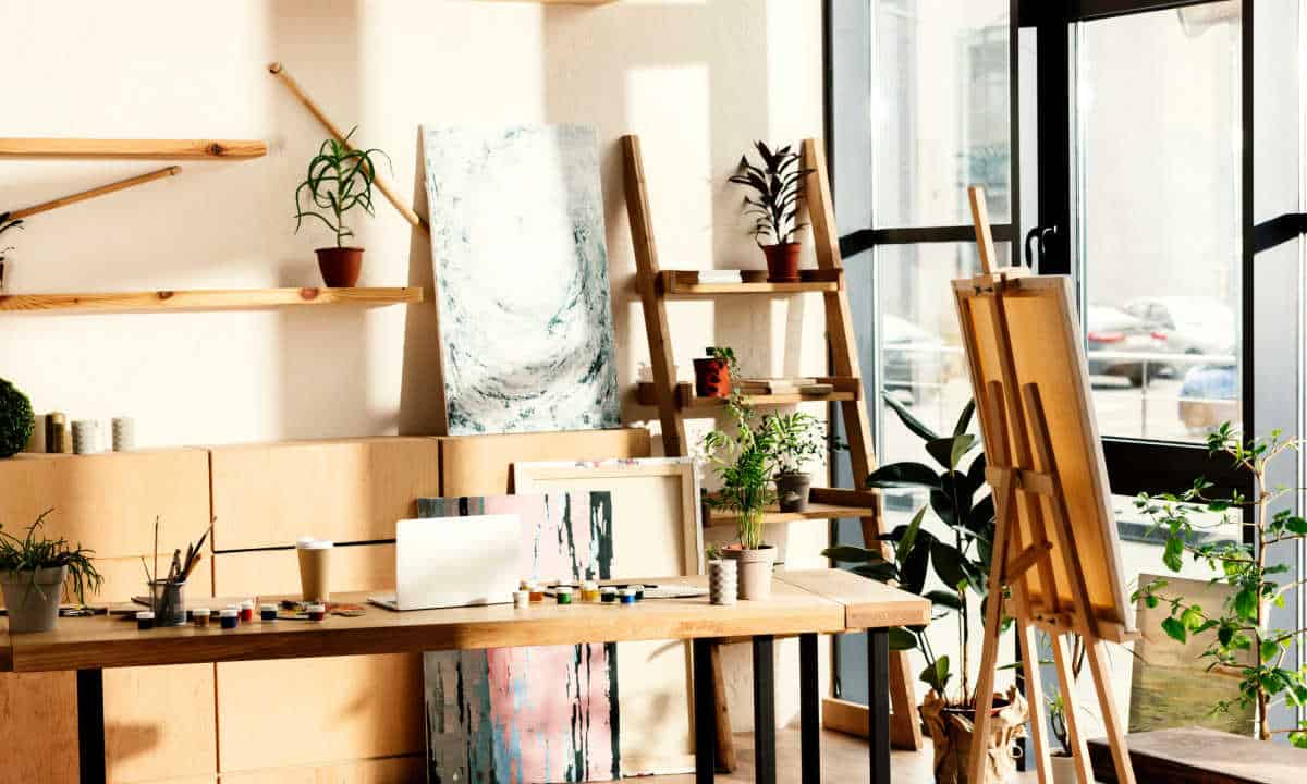 An artist's studio with a bench, paints, an easel, and canvases.