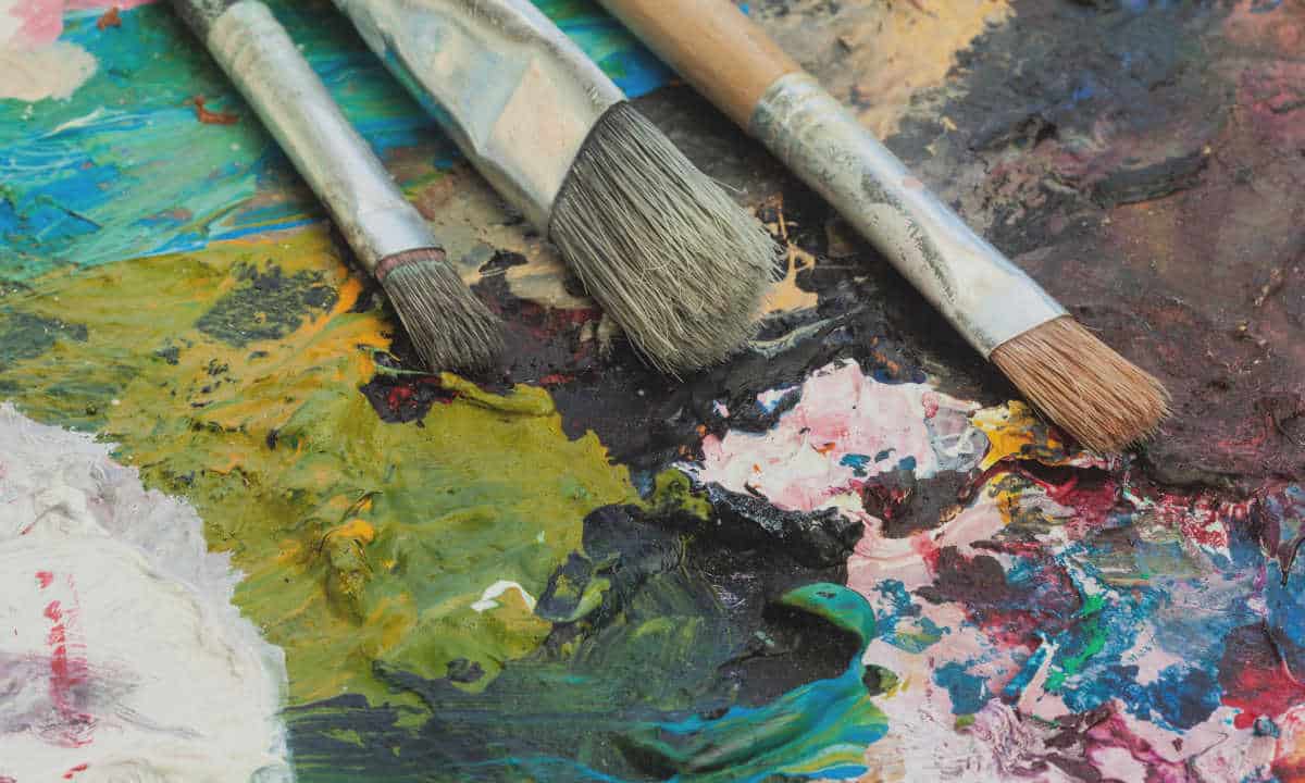 A close up of paint brushes and paint on a palette.