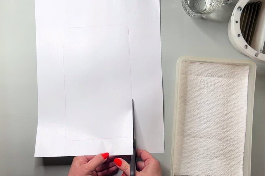 An artist cutting a sheet of palette paper to fit into a diy wet palette.